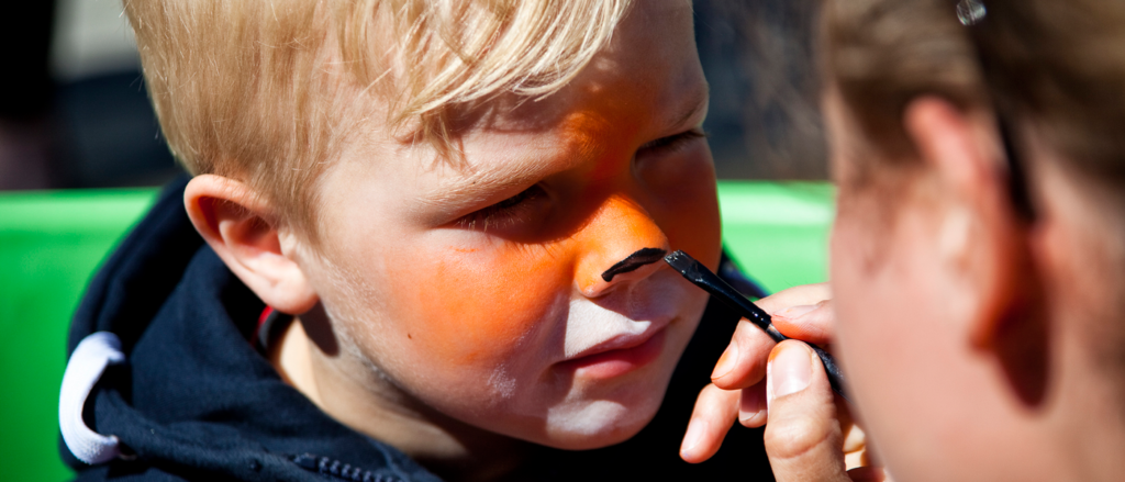 Pojke målas i ansiktet med ansiktsfärg