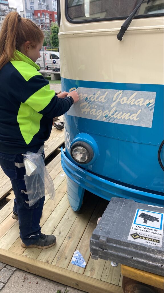 Arbetare som målar till texten "Harald Johan Hägglund" på vagnen