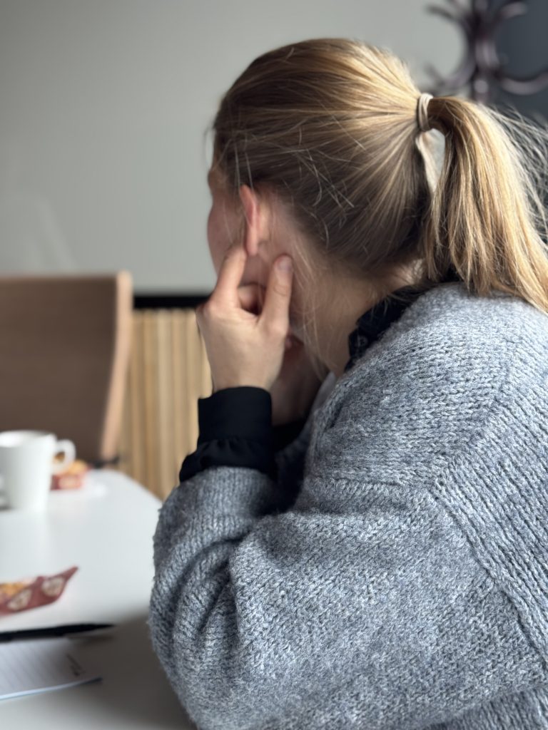 Utvecklingsledare håller för öronen under praktisk övning som handlar om hörselnedsättningar.