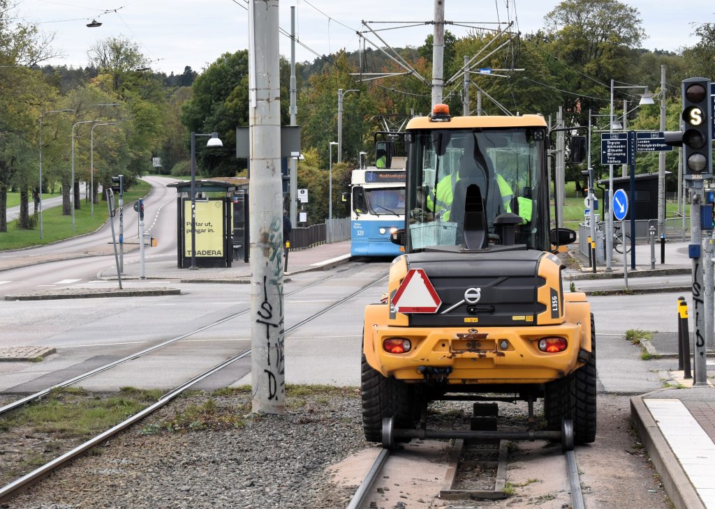 En gul liten traktor som kör på spårvagnsspår.