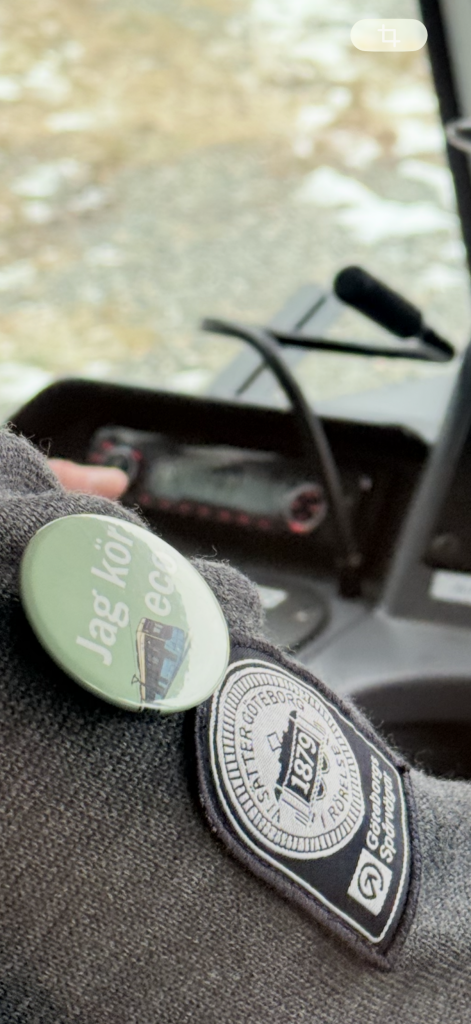 En grön pin på en grå kofta där det står Jag kör eco.