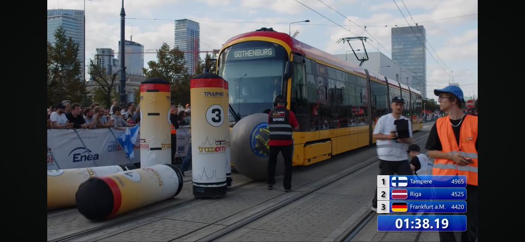 En gul-röd spårvagn kör ner stora käglor med en stor boll.