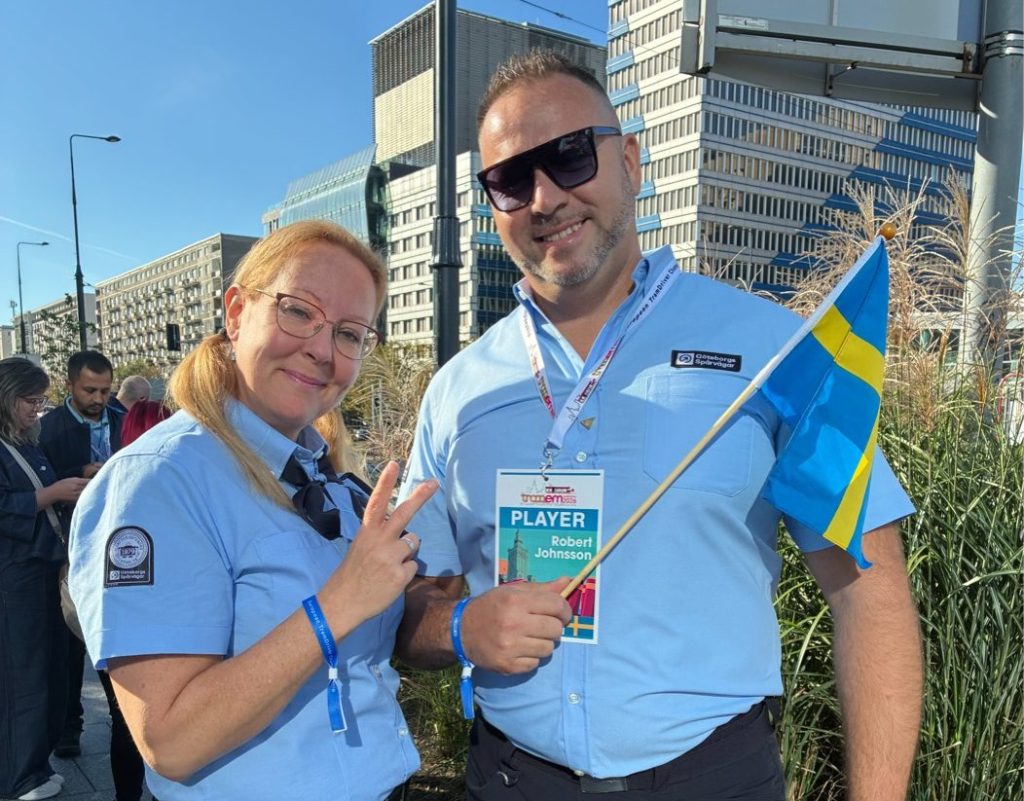 Spårvagnsförarna Jeanette och Robert i ljusblå skjortor och med en svensk flagga
